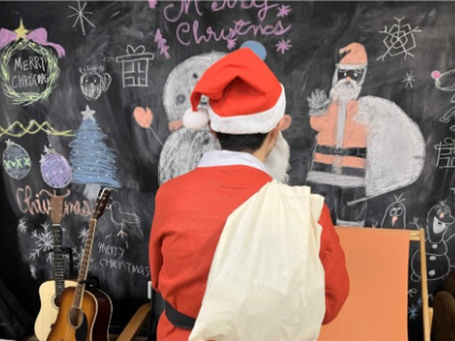 サンタクロースに扮したスタッフと、クリスマスの絵が描かれた黒板